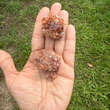 Hand holding two crystal rocks with a grassy background