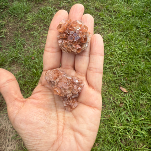 Hand holding two crystal rocks with a grassy background