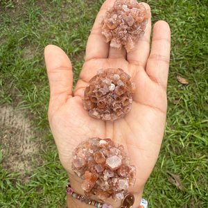 Hand holding three crystal clusters with a grassy background