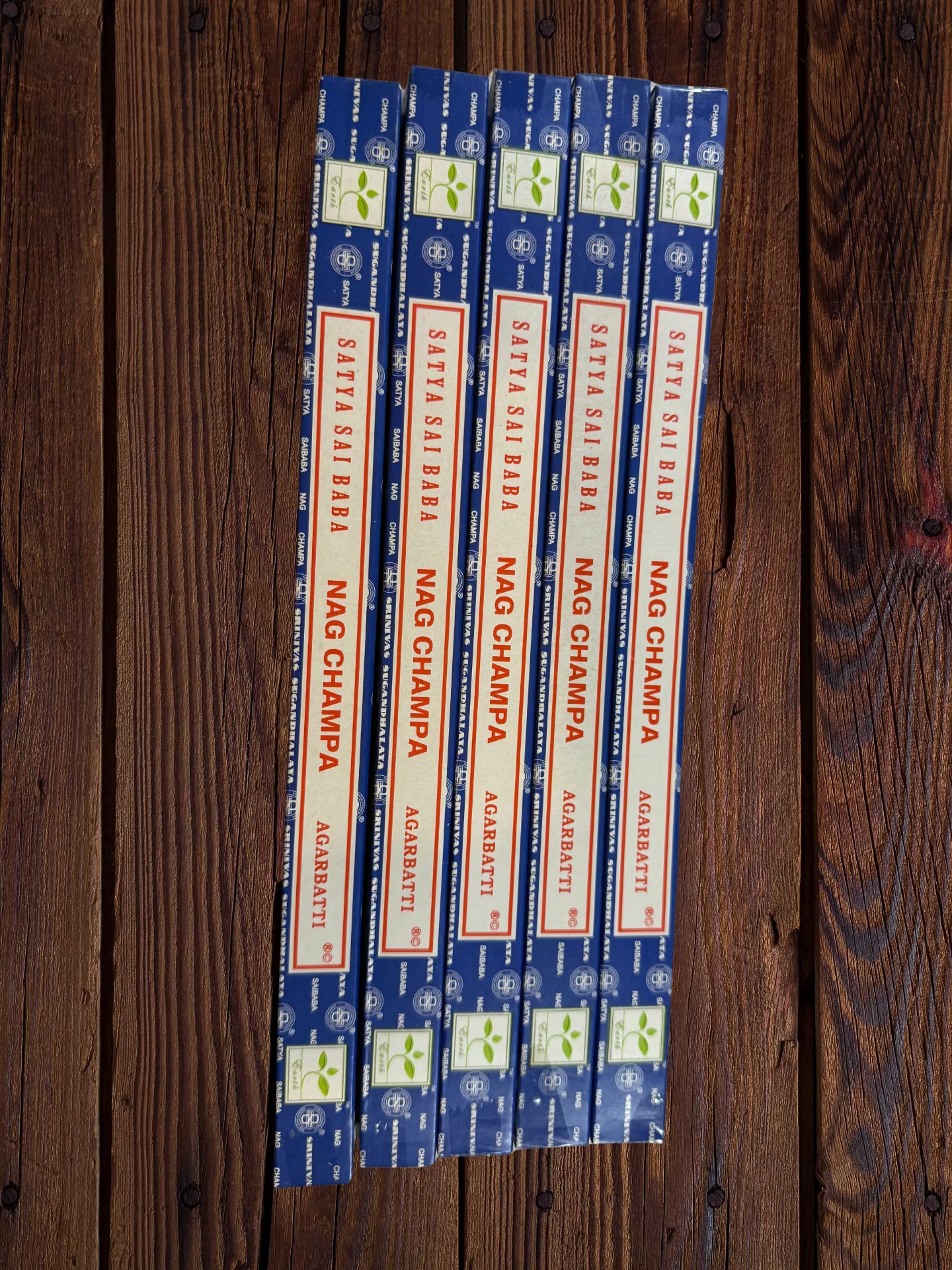 Five Satya Sai Baba Nag Champa 10g incense packages on a white brick background
