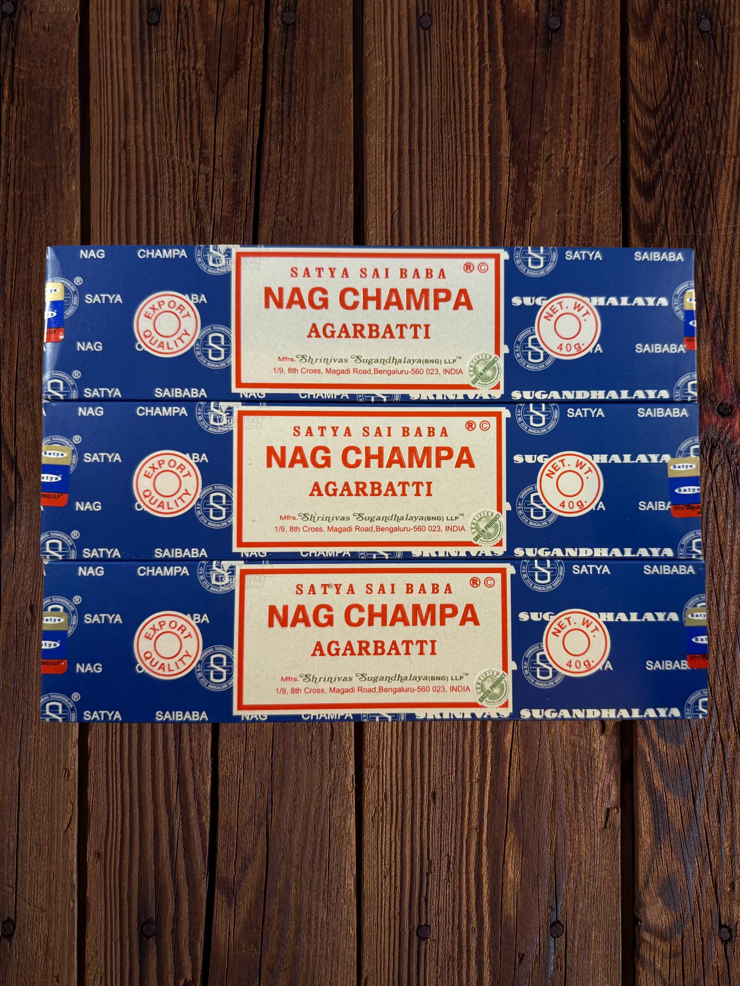 Three Satya Sai Baba Nag Champa 40g incense packages arranged on wood
