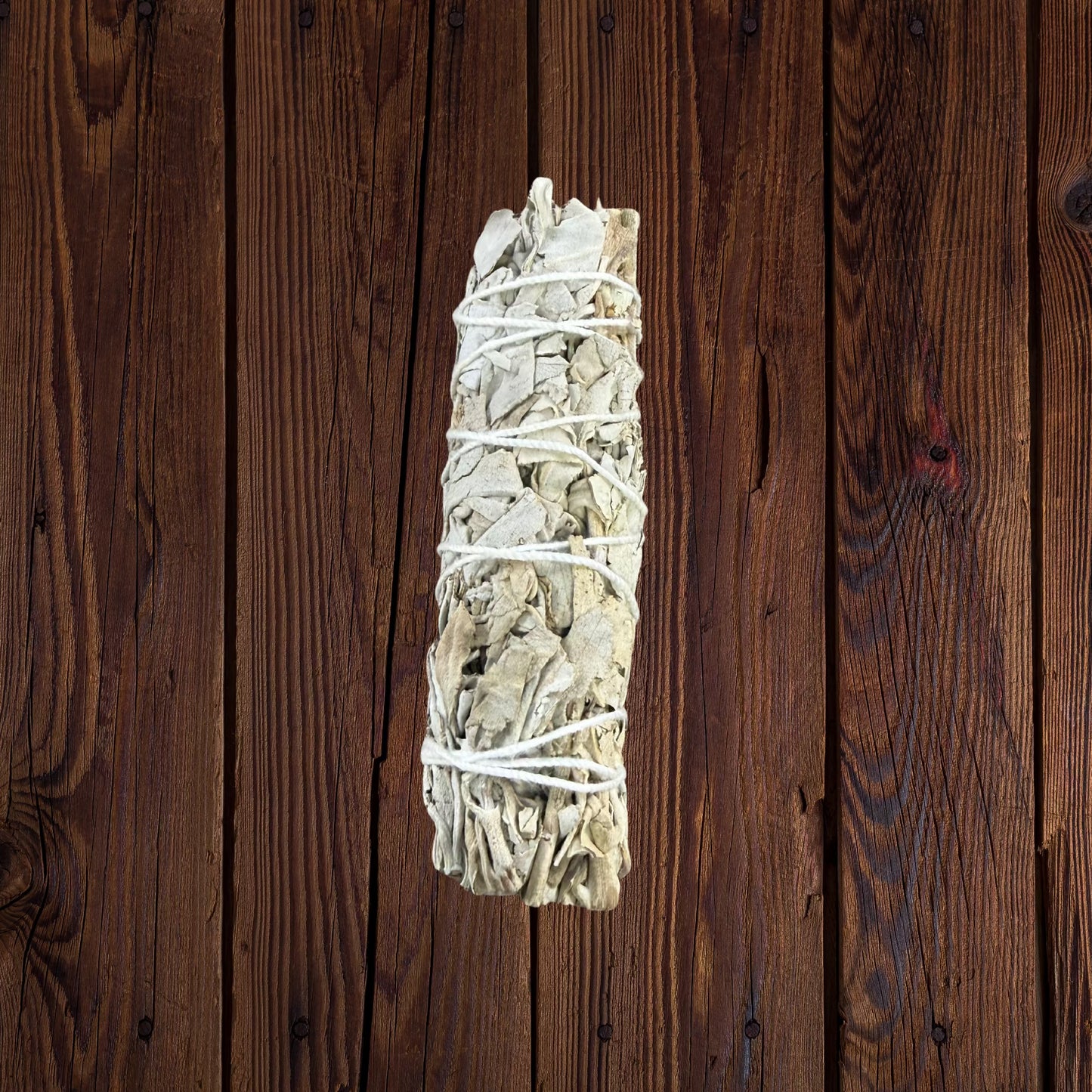 Single white sage smudge stick on dark wood