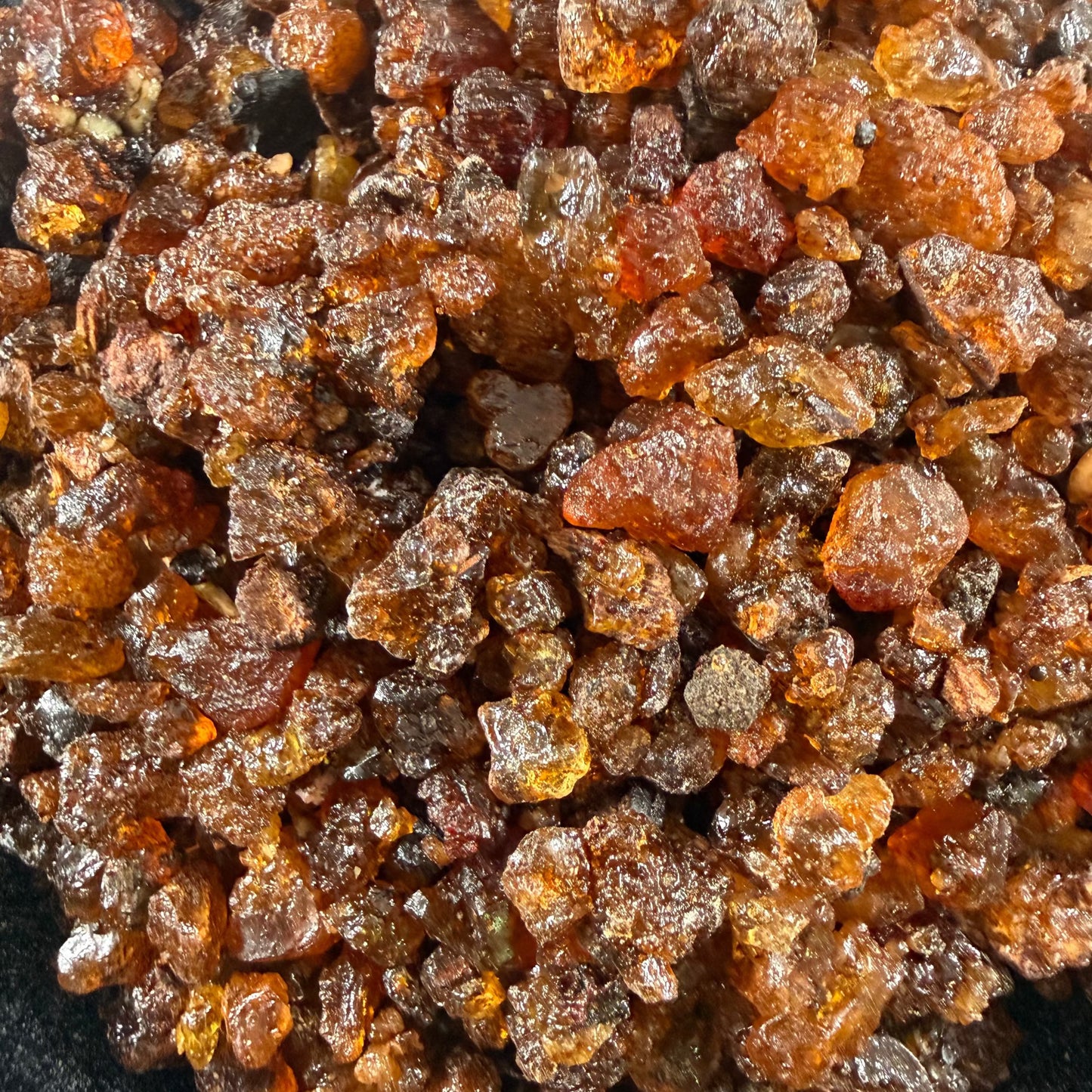 Myrrh resin granules showing varied shapes and rich reddish-brown and golden tones.