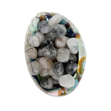 Tourmalinated Quartz tumbles in a small pile inside avalone shell – polished crystals for meditation and grounding