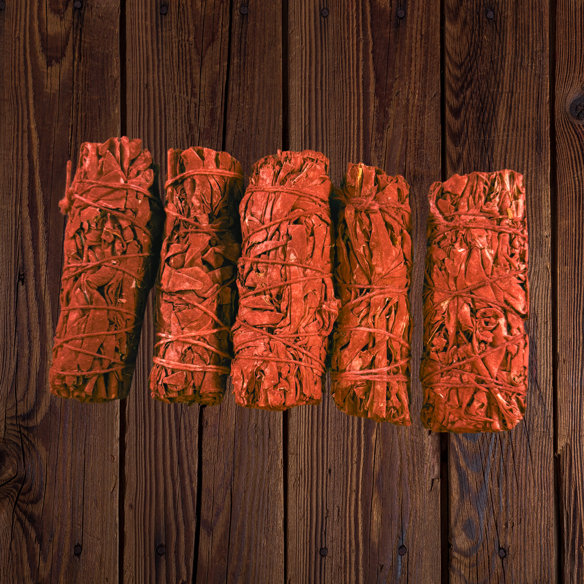 Five Dragon’s Blood white sage smudge sticks arranged side by side on dark wood